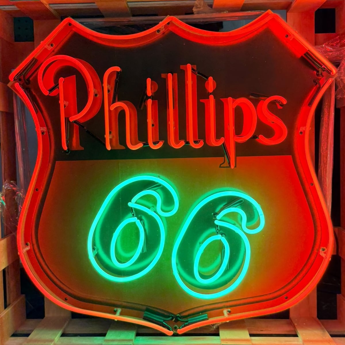 Archived catalog photograph of an illuminated shield-shaped Phillips 66 display with red lettering, green numerals, and red border