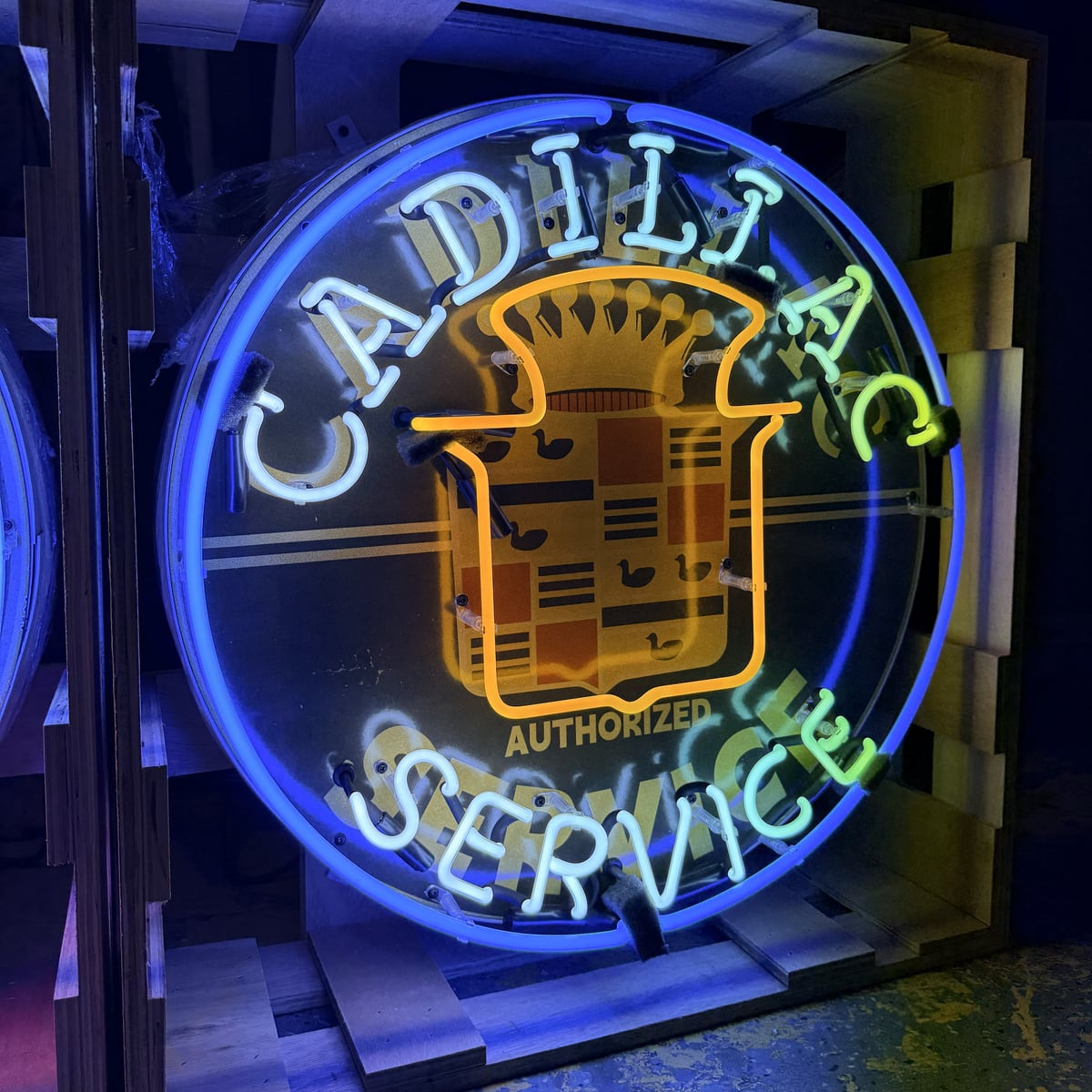 Archived catalog photograph of an illuminated round Cadillac-themed display with crest graphic and blue-and-white formed-glass lettering