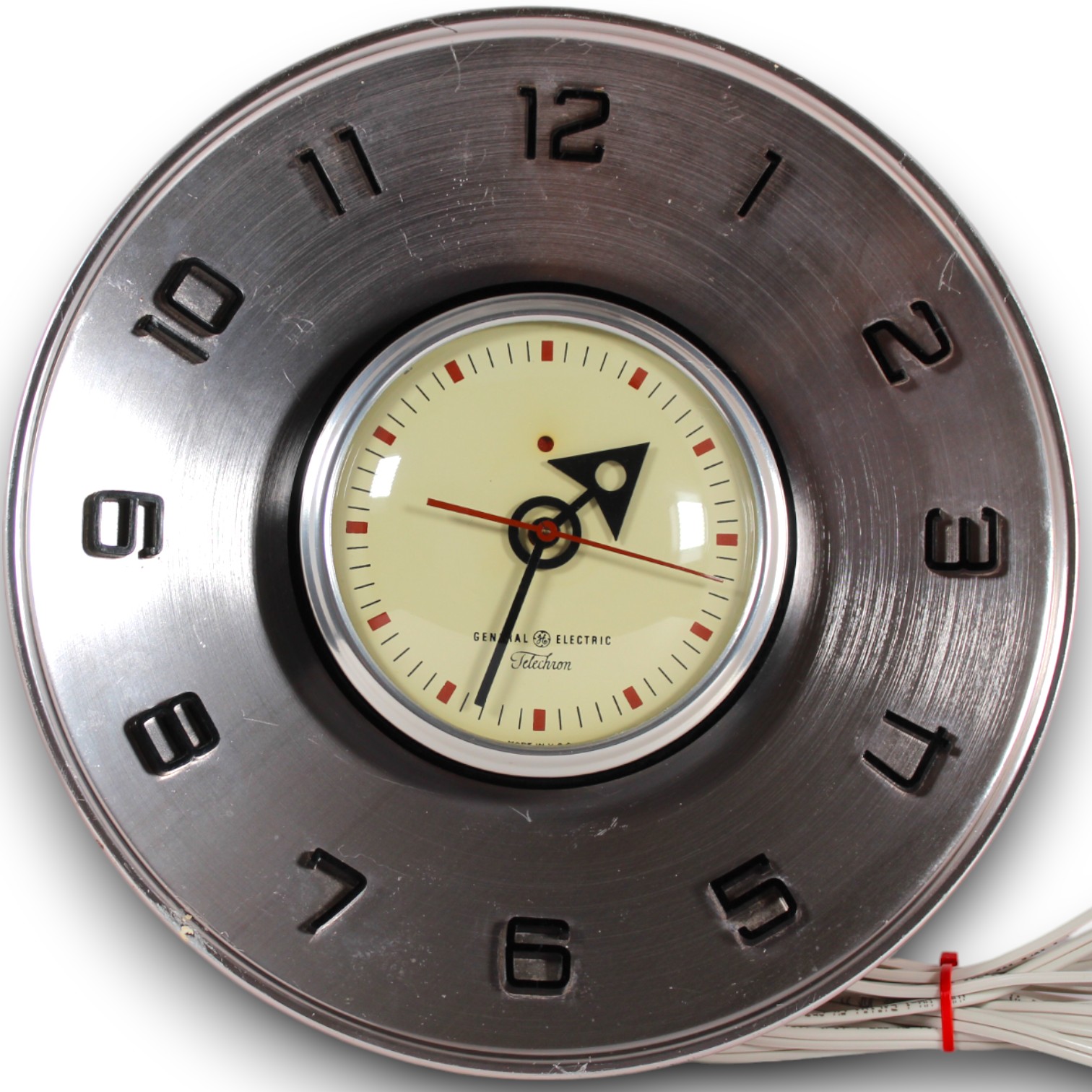 Catalog photograph of a round Telechron wall clock with a brushed-metal outer dial, cream center, and red accents