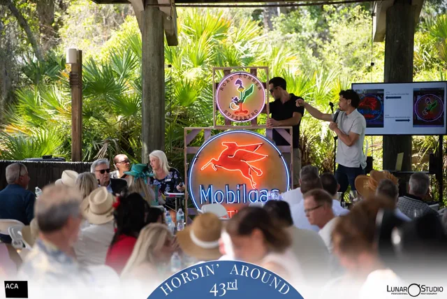 Darrien Eouse presenting illuminated advertising signs at the 2026 Horsin’ Around benefit auction